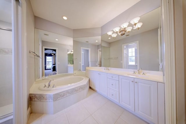 bathroom featuring tiled tub, vanity, a notable chandelier, and tile patterned floors