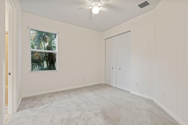 unfurnished bedroom featuring ceiling fan, light colored carpet, and a closet