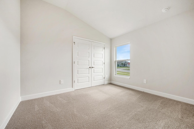 unfurnished bedroom featuring lofted ceiling, carpet floors, and a closet