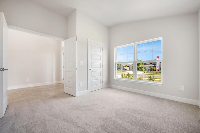 unfurnished bedroom featuring light carpet and vaulted ceiling