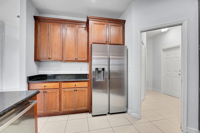 kitchen featuring light tile patterned floors, dark stone counters, and appliances with stainless steel finishes