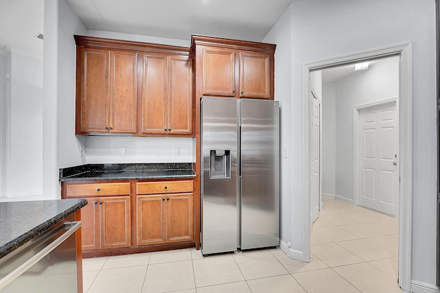 kitchen featuring dark stone countertops, light tile patterned floors, and stainless steel appliances