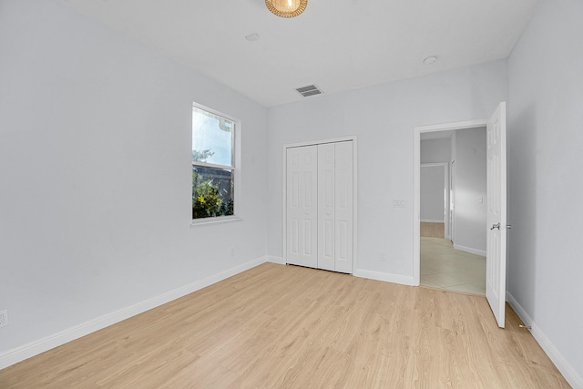 unfurnished bedroom with light hardwood / wood-style flooring and a closet