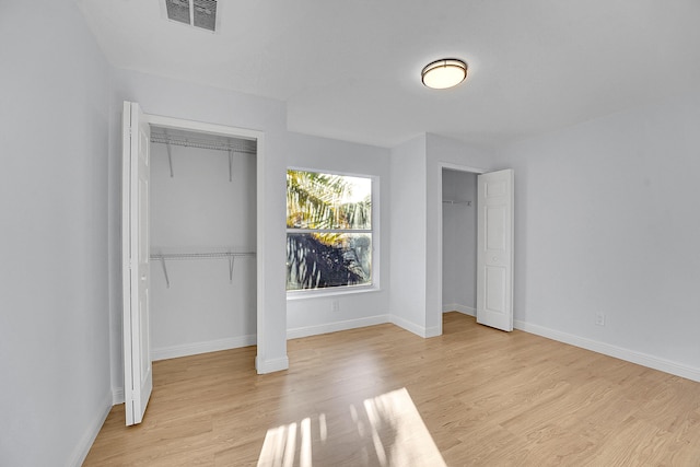 unfurnished bedroom with light hardwood / wood-style floors and multiple closets