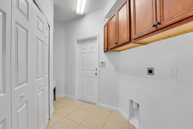 washroom with cabinets, electric dryer hookup, and light tile patterned flooring