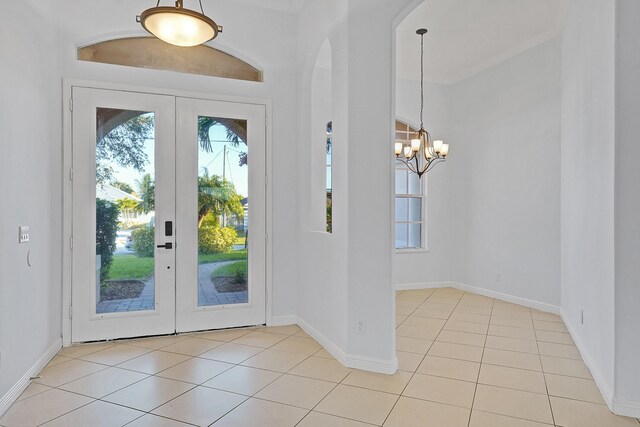 entryway featuring french doors, an inviting chandelier, and light tile patterned floors