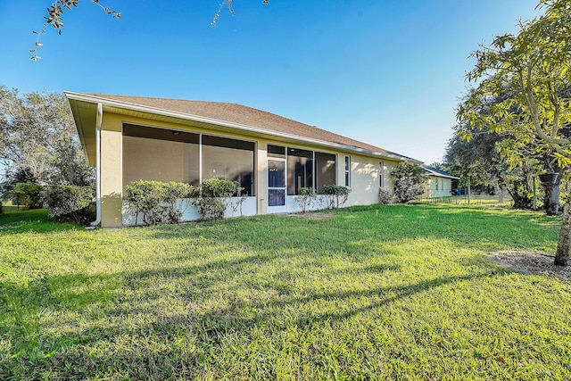 rear view of house featuring a yard and a sunroom