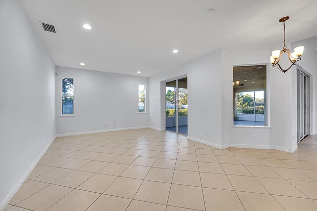 spare room with light tile patterned flooring and an inviting chandelier