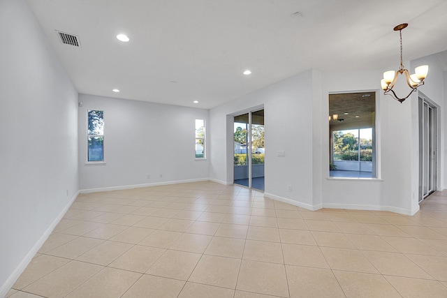 unfurnished room with light tile patterned flooring and a chandelier