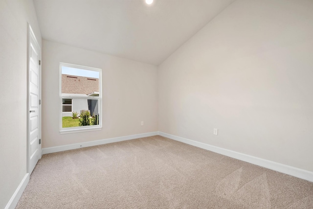 carpeted empty room with vaulted ceiling