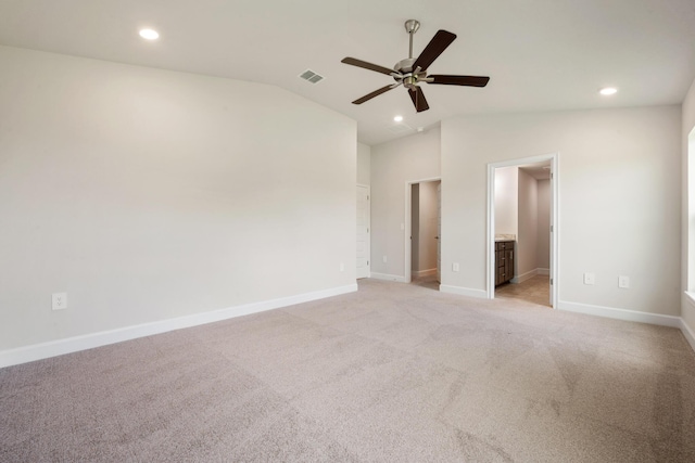 unfurnished bedroom featuring ceiling fan, vaulted ceiling, light carpet, and ensuite bath