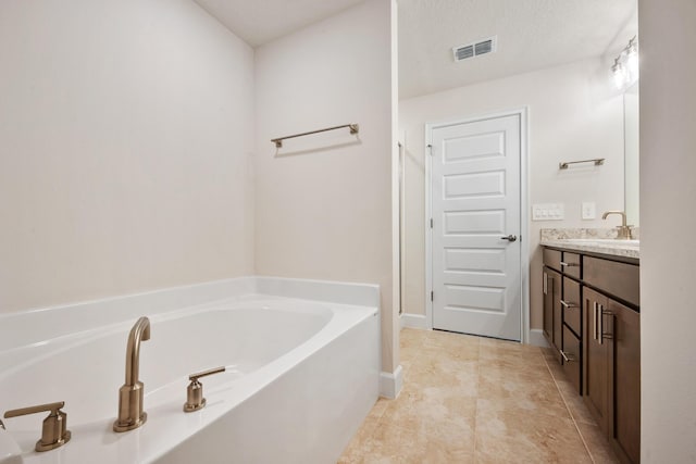 bathroom featuring a textured ceiling, vanity, tile patterned floors, and a bathtub