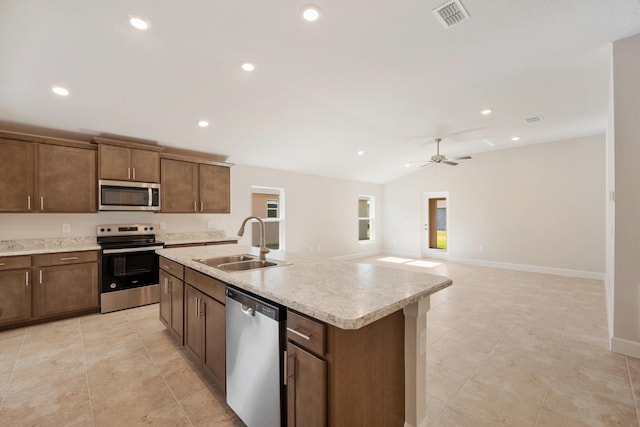 kitchen featuring appliances with stainless steel finishes, vaulted ceiling, ceiling fan, a kitchen island with sink, and sink