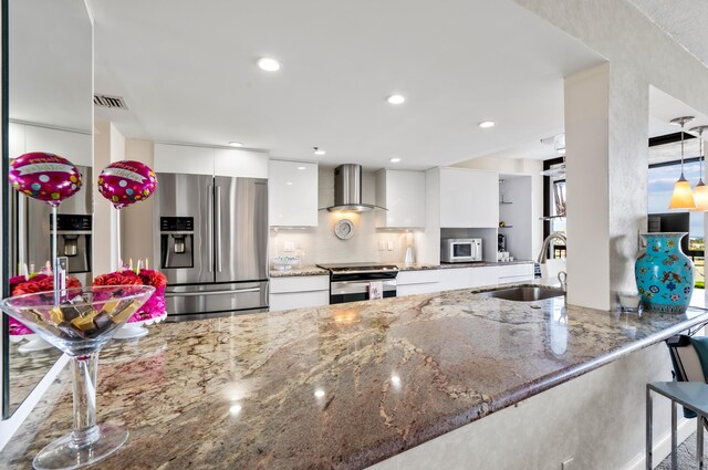 kitchen featuring wall chimney exhaust hood, a sink, white cabinetry, modern cabinets, and appliances with stainless steel finishes