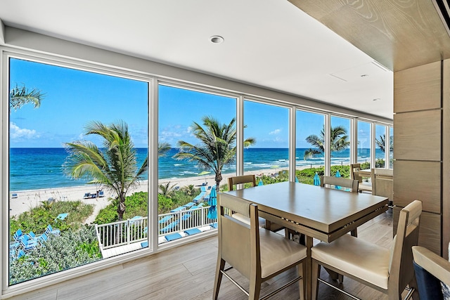 sunroom with a water view, a beach view, and a wealth of natural light