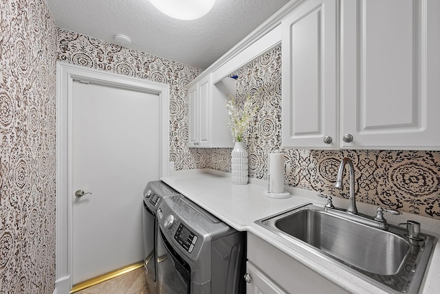 laundry room featuring washer and clothes dryer, cabinets, sink, and a textured ceiling