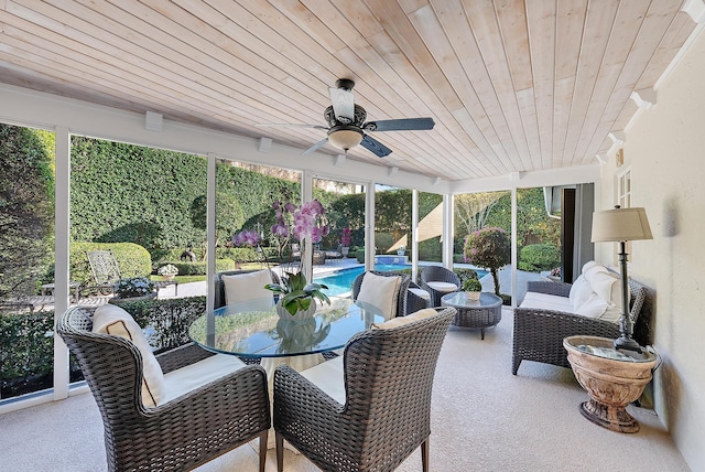 sunroom / solarium featuring a healthy amount of sunlight, ceiling fan, and wooden ceiling