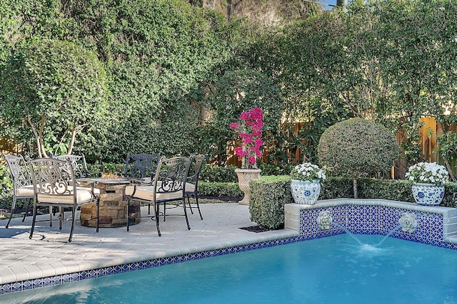 view of swimming pool with pool water feature, a patio area, and an outdoor fire pit