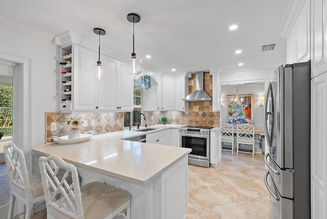 kitchen with pendant lighting, white cabinets, wall chimney range hood, kitchen peninsula, and stainless steel appliances