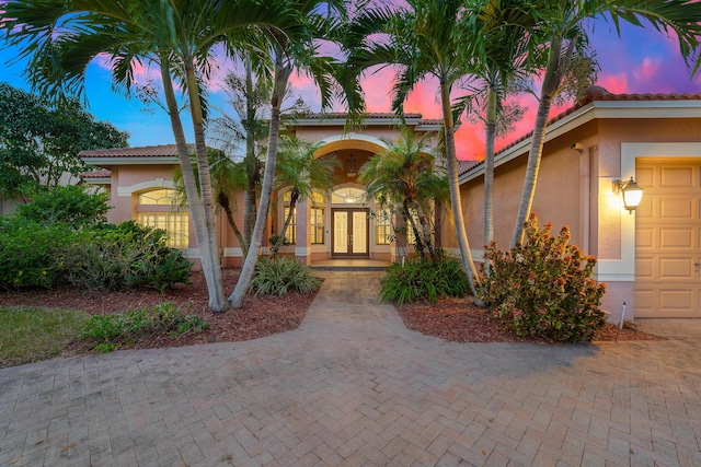 exterior entry at dusk featuring french doors and a garage