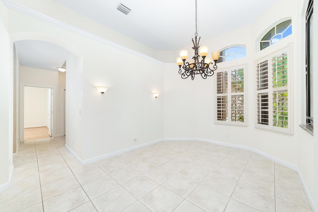 spare room featuring light tile patterned flooring and a notable chandelier