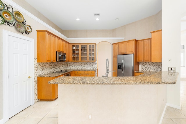 kitchen featuring backsplash, kitchen peninsula, light stone counters, and appliances with stainless steel finishes