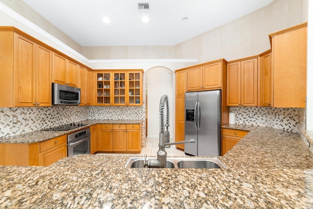 kitchen with backsplash, stone counters, sink, and appliances with stainless steel finishes