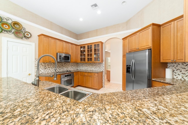 kitchen with backsplash, stainless steel appliances, sink, light tile patterned floors, and stone counters