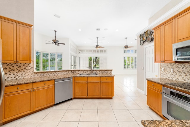 kitchen featuring appliances with stainless steel finishes, backsplash, light stone counters, and light tile patterned floors