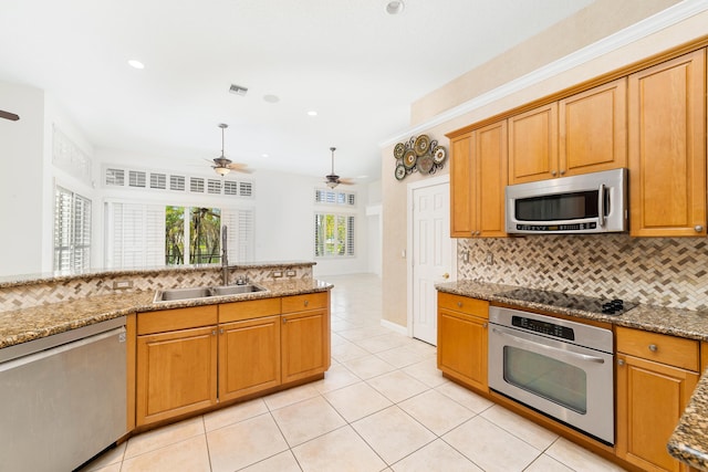 kitchen featuring appliances with stainless steel finishes, backsplash, light stone counters, and sink