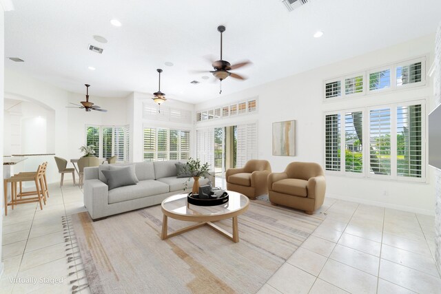 living room with ceiling fan, a towering ceiling, and light tile patterned floors