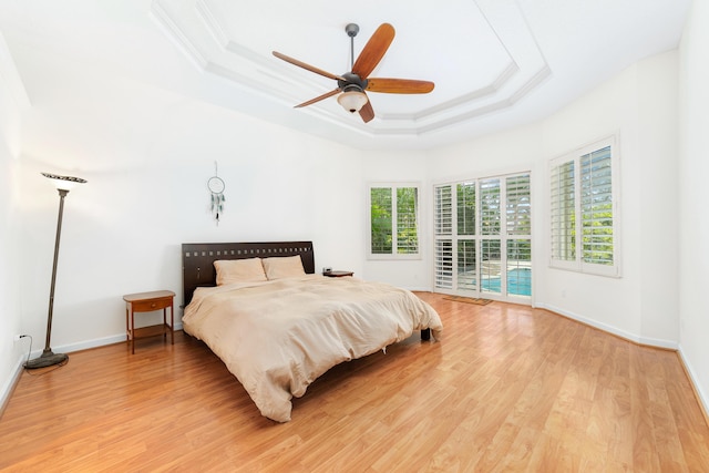 bedroom featuring a raised ceiling, ceiling fan, light hardwood / wood-style floors, and access to outside