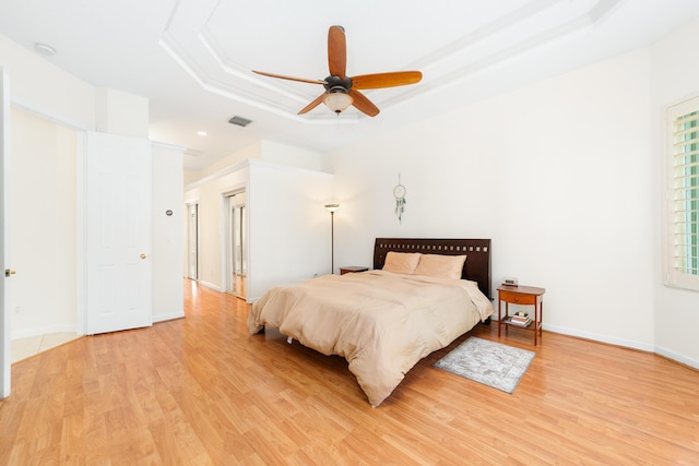 bedroom featuring a tray ceiling, light hardwood / wood-style flooring, and ceiling fan