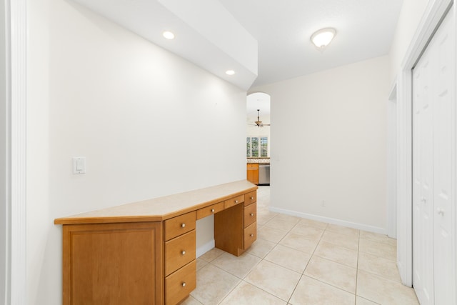 unfurnished office featuring ceiling fan, built in desk, and light tile patterned floors