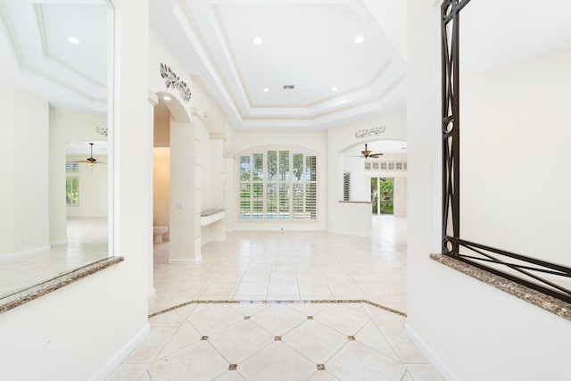 interior space with a raised ceiling, ceiling fan, and crown molding