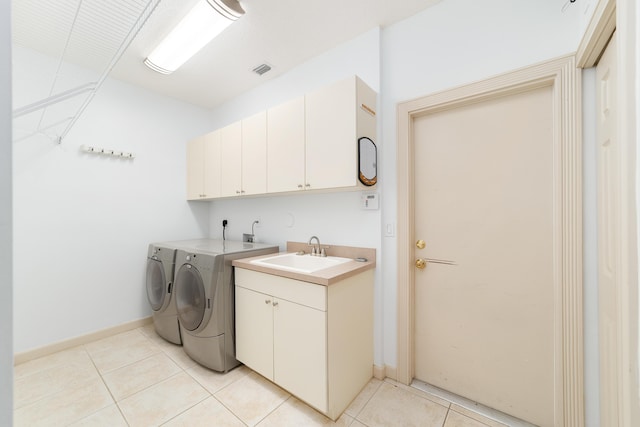 laundry room with washer and clothes dryer, light tile patterned flooring, cabinets, and sink