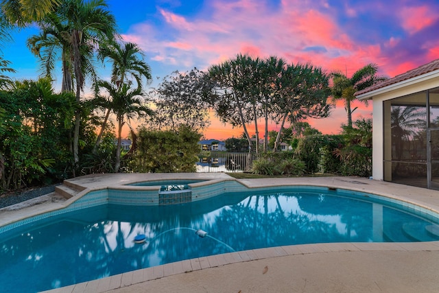 pool at dusk with an in ground hot tub