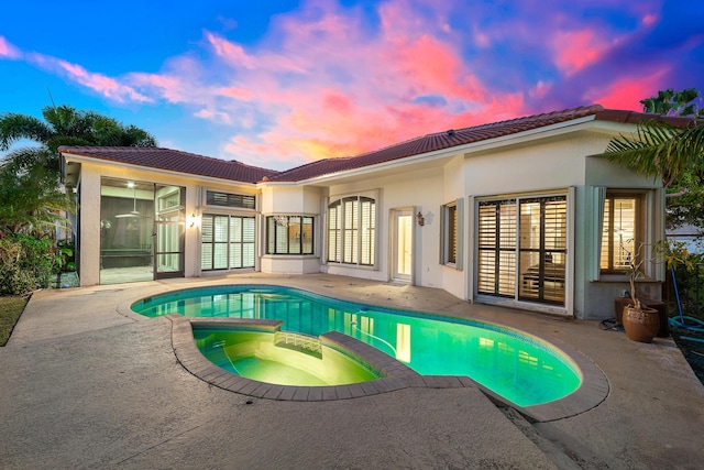 pool at dusk with a patio area and an in ground hot tub