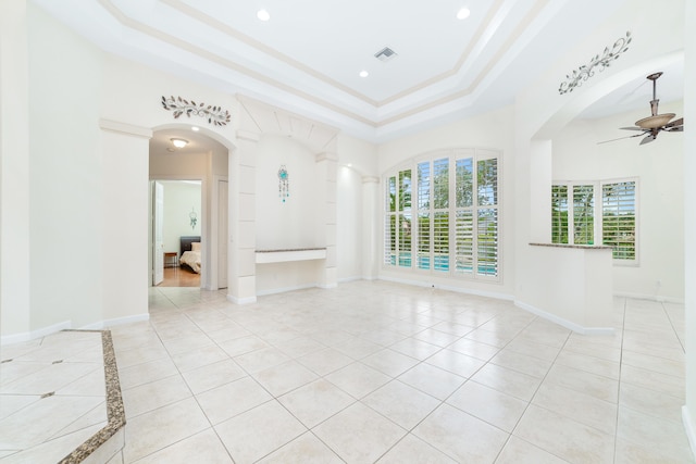 unfurnished living room with a tray ceiling, a wealth of natural light, ceiling fan, and light tile patterned floors