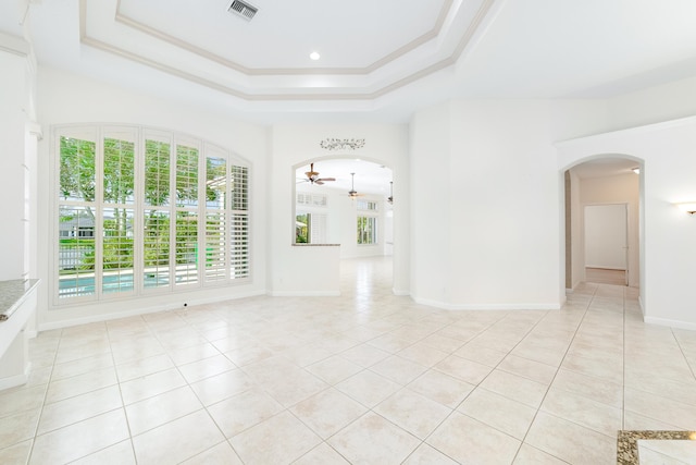 spare room featuring a raised ceiling, ceiling fan, light tile patterned floors, and ornamental molding