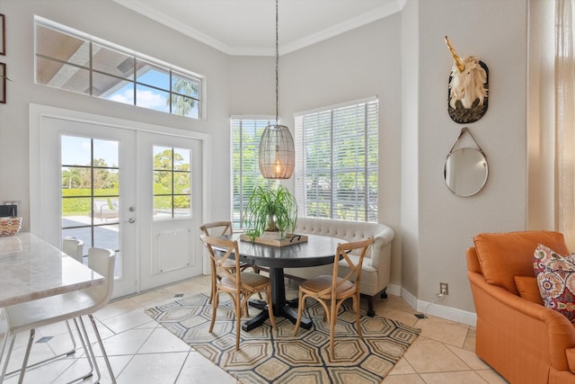 tiled dining space featuring a towering ceiling, crown molding, and french doors