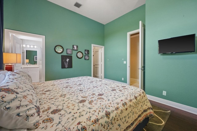 bedroom featuring ensuite bathroom, wood-type flooring, and a towering ceiling