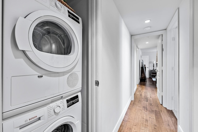 laundry room with light hardwood / wood-style floors and stacked washer / dryer