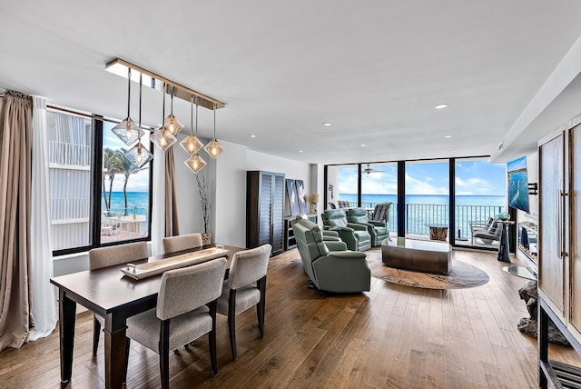 dining room featuring hardwood / wood-style floors, a water view, floor to ceiling windows, and a healthy amount of sunlight