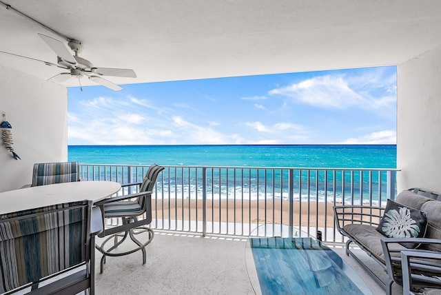 balcony featuring a beach view, a water view, and ceiling fan