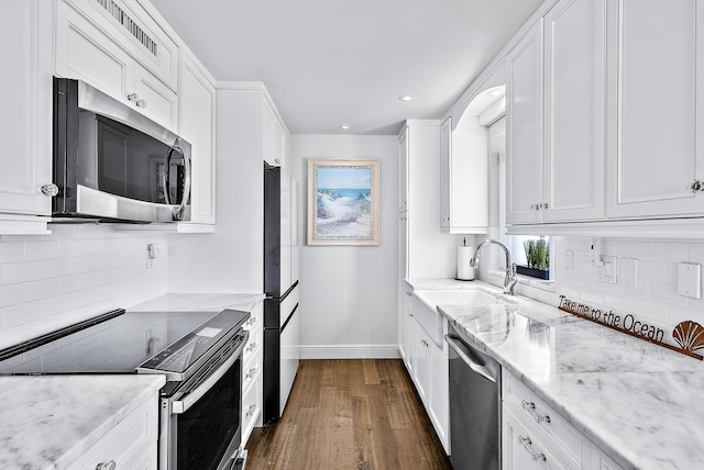 kitchen with light stone countertops, sink, dark hardwood / wood-style floors, white cabinets, and appliances with stainless steel finishes