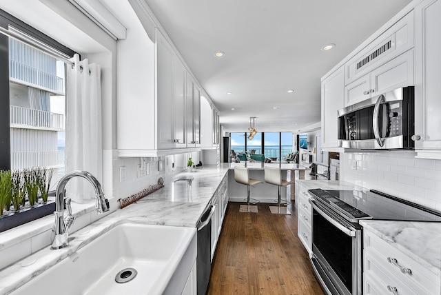 kitchen with white cabinets, appliances with stainless steel finishes, dark hardwood / wood-style floors, and sink