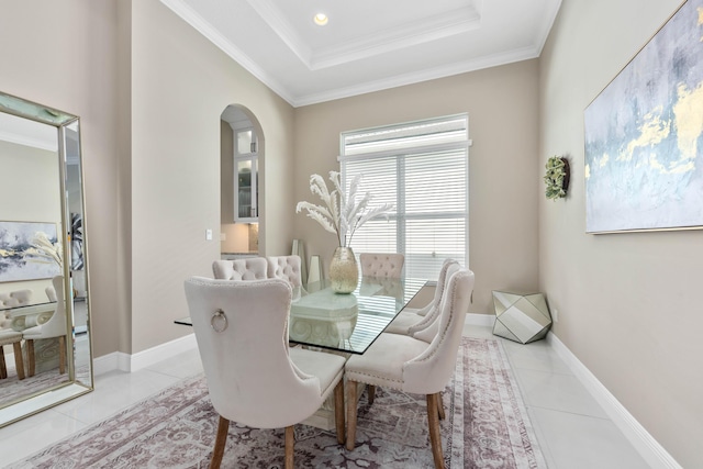 tiled dining room with ornamental molding and a tray ceiling