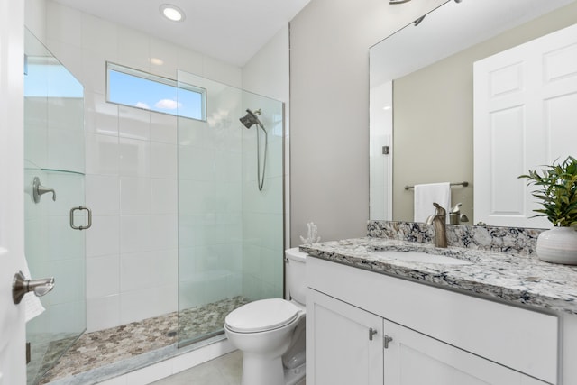 bathroom featuring vanity, toilet, and a shower with door