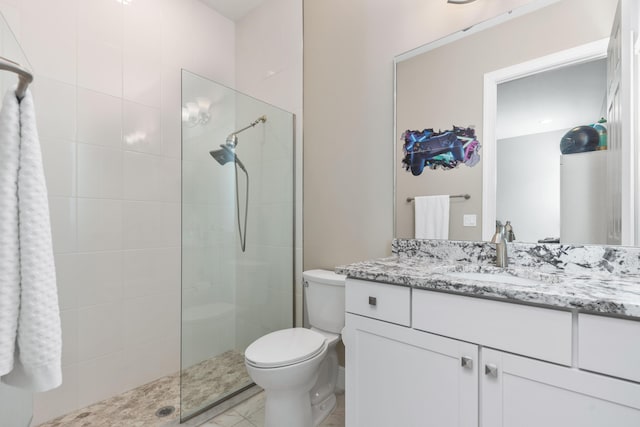 bathroom with a tile shower, vanity, and toilet